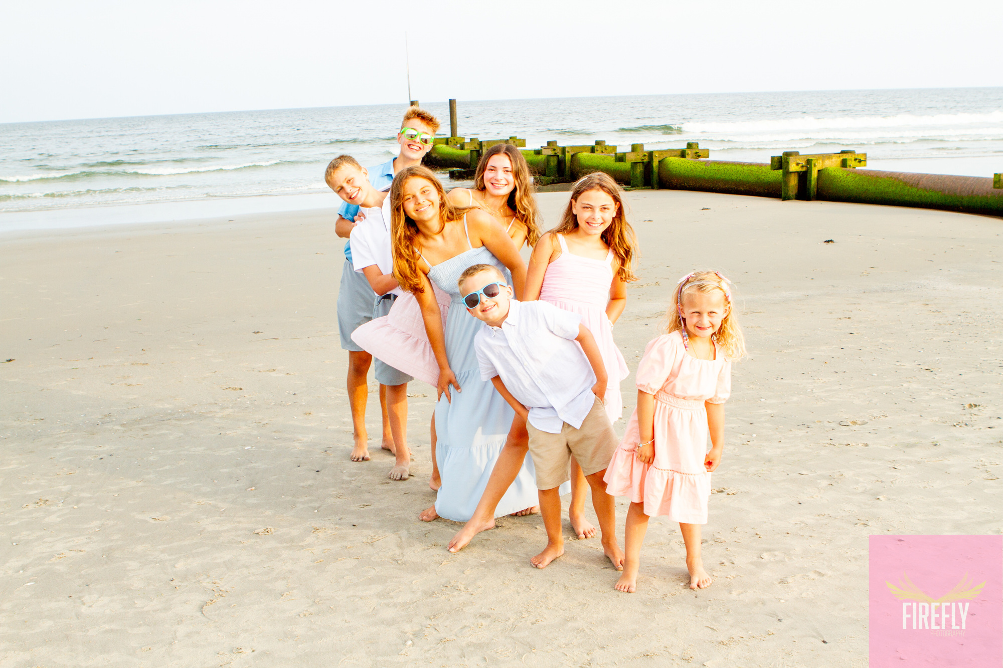 Cousins playful beach portrait by the jetty